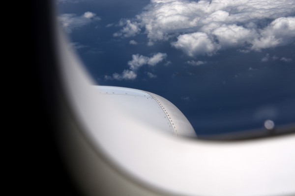 Lot samolotem | Zdjęcie przedstawi widok z okna samolotu, niebieskie niebo i małe białe chmury